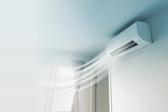 Intérieur moderne avec climatiseur mural blanc en fonctionnement, flux d'air visible soufflant vers des rideaux blancs flottants près d'une fenêtre